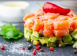 Délicieuse salade d'avocat et de saumon cru, tartare, servie sur une plaque noire au citron vert, fond clair