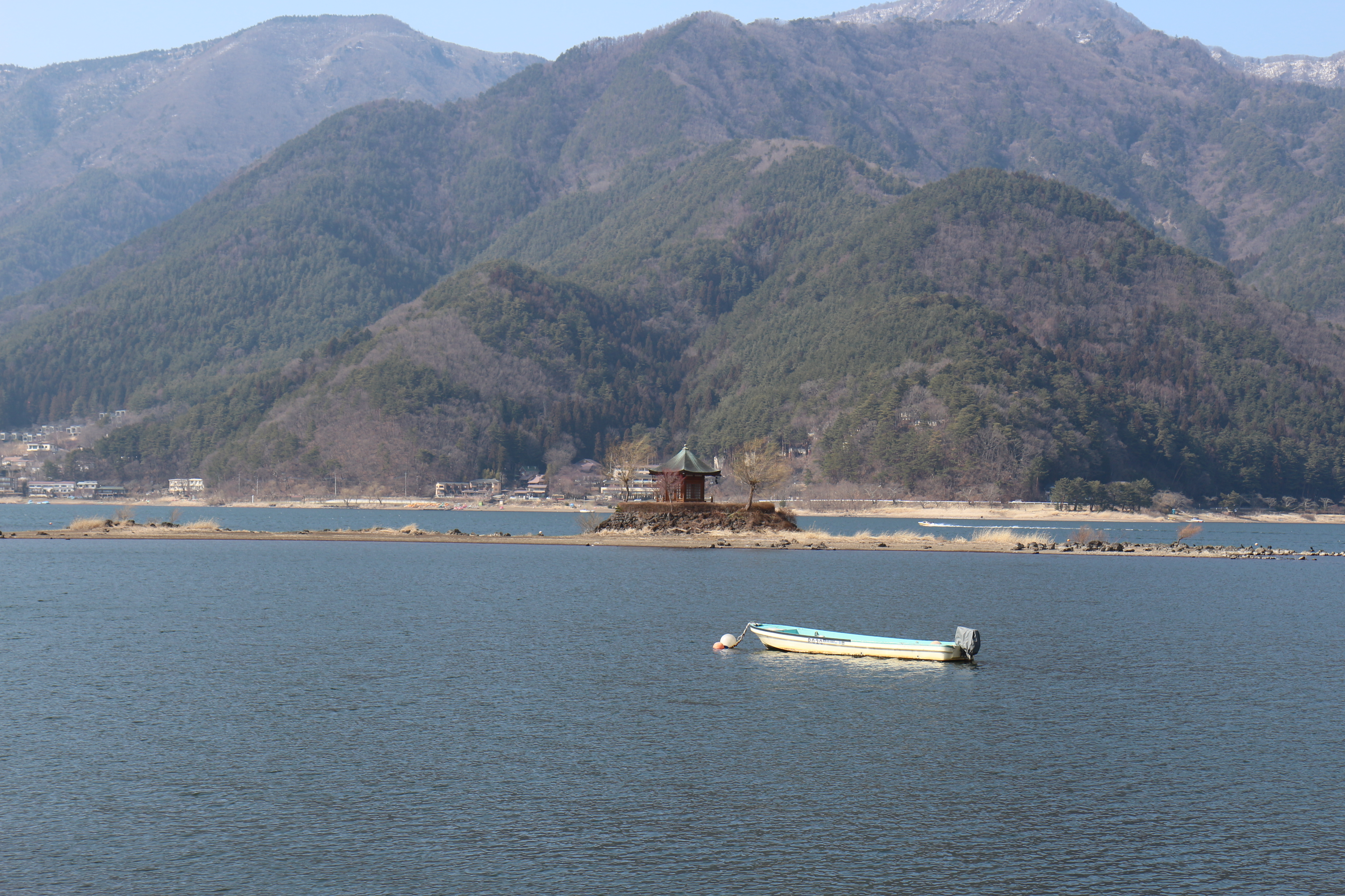 Photo du sanctuaire sur le petit îlot du lac Kawaguchiko. Une barque est ancrée au premier plan.